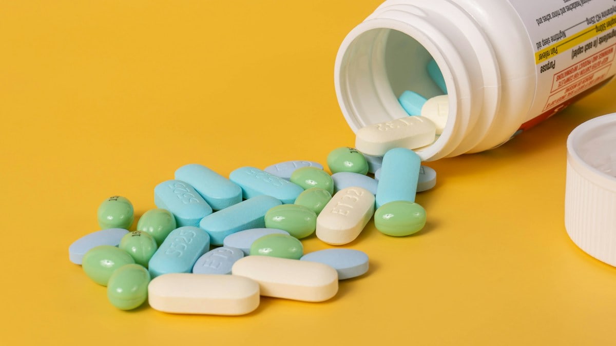 Mixed pills spilling out of a pill bottle.